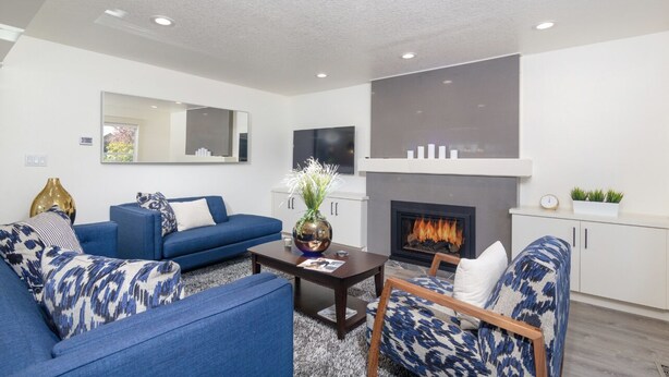 A modern living room with a fireplace, blue sofas, and a flat-screen TV. - Full House ➡️ Hut Tub (Aloha)