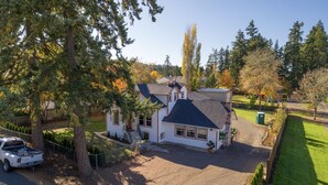 A two-story house with a sloped roof, a fenced yard, and a parked truck. - Full House ➡️ Hut Tub (Aloha)