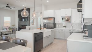 Une cuisine moderne avec des meubles blancs, un îlot central et des luminaires suspendus.