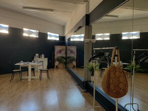 A room with a wooden floor, a table with chairs, a mirror, and a hanging bag. - Seasonal Rental: 100 m&sup2; dance studio to be furnished<br>, in the center of Cahors (Cahors)