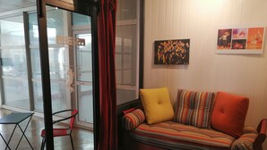 Ein gemütlicher Wohnbereich mit einer Couch, einem roten Sessel und einer Glastür zum Balkon.
