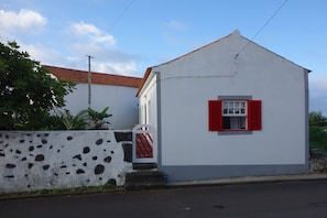 A small, single-story building with a white facade and a red window shutter.