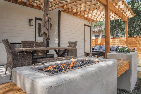An outdoor patio with a concrete fire feature, wicker furniture, and a wooden pergola.