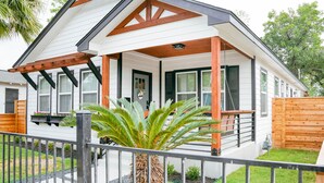 A house with a covered porch, a wooden fence, and a palm tree in the yard.