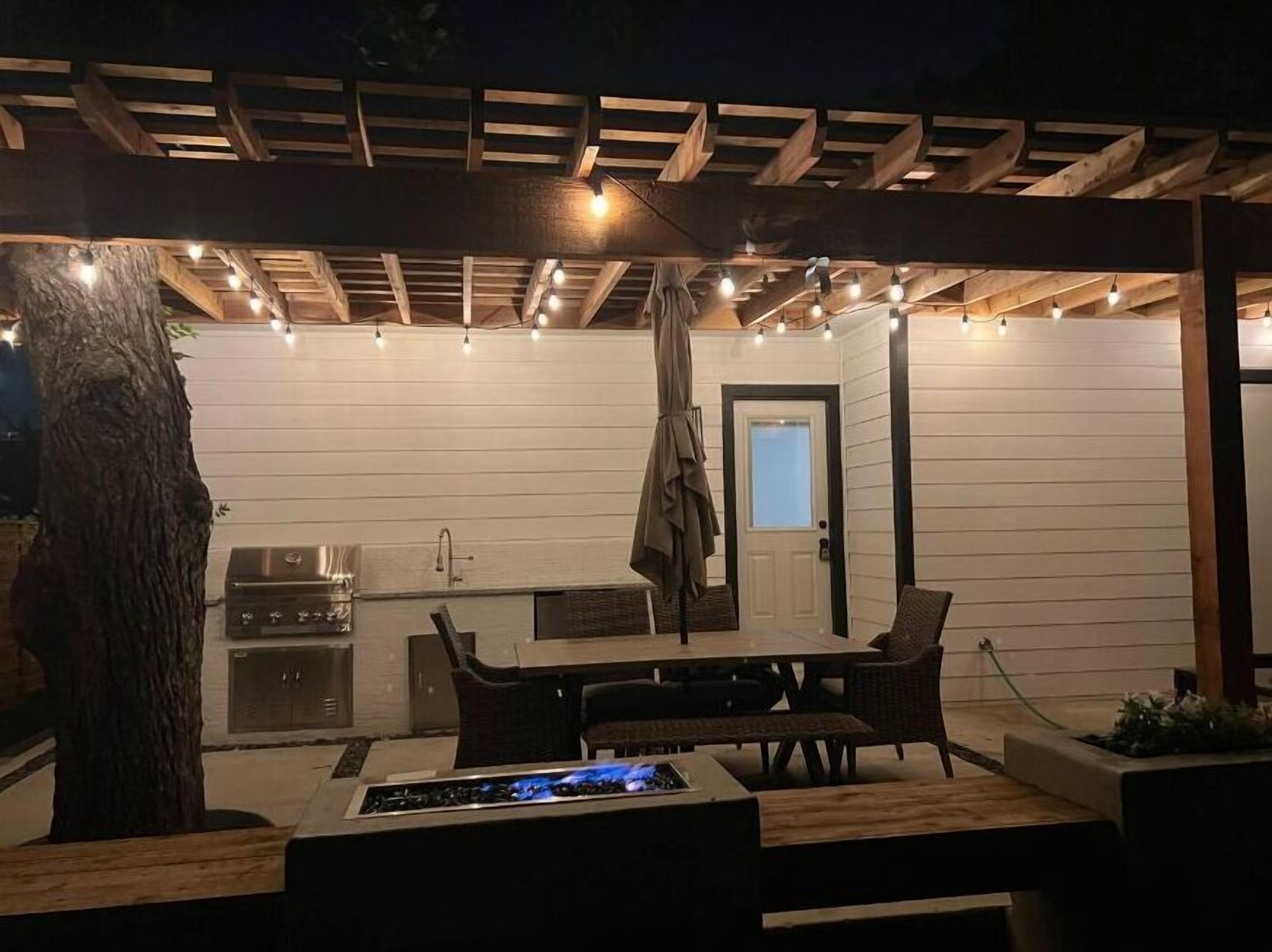 Eine Terrasse im Freien mit Grill, Sitzgelegenheit und Lichterkette.