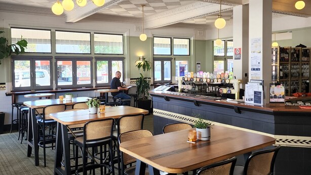 A restaurant interior with high ceilings, decorative moldings, and a bar area. Tables and chairs are arranged for dining. - The Young Street Hotel (Carrington)