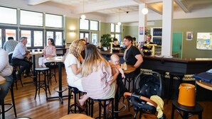 A restaurant interior with wooden floors, round tables, and black bar stools. - The Young Street Hotel (Carrington)