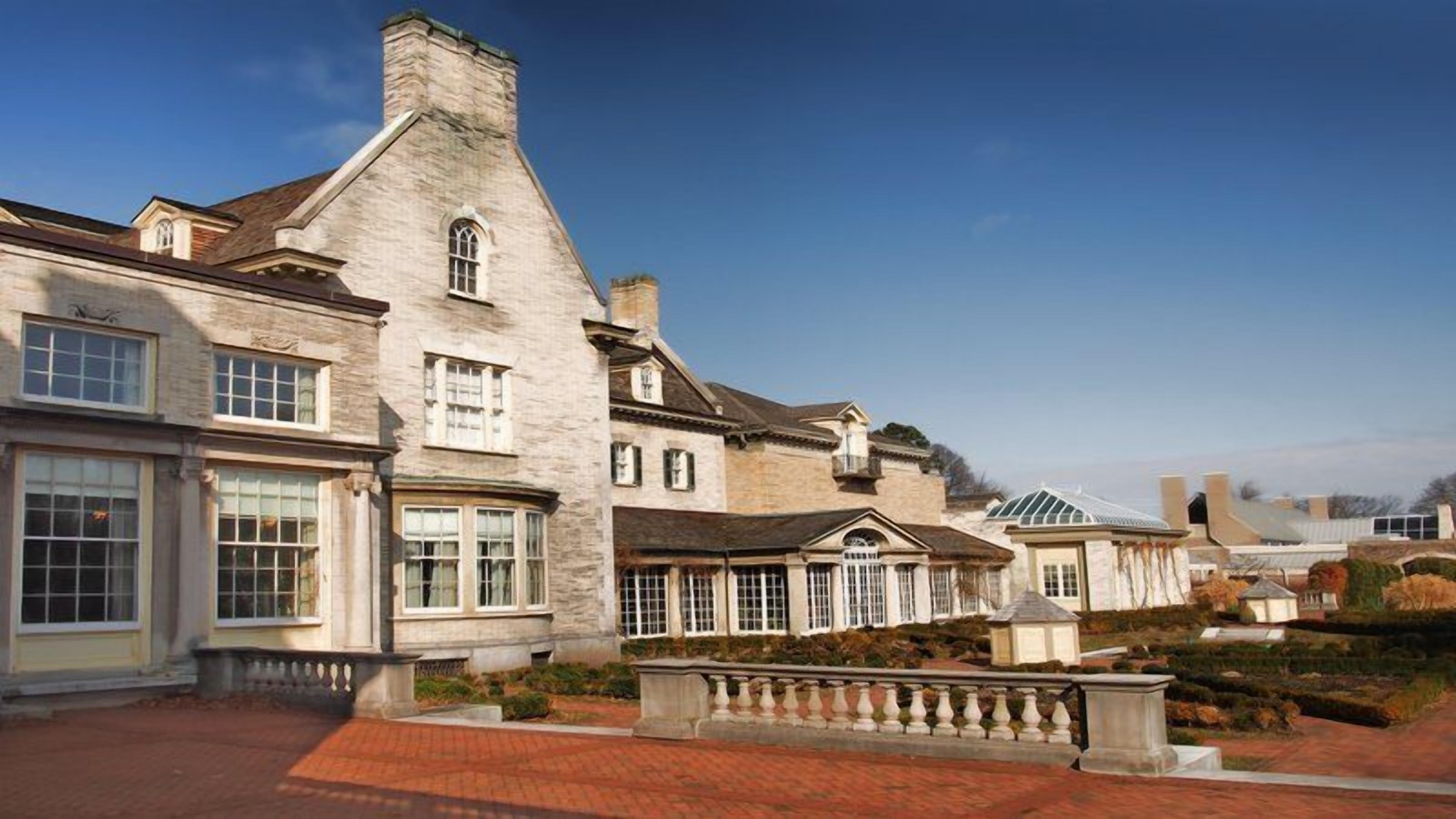 A large, historic building with multiple windows and a brick pathway.