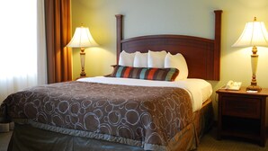 Een hotelkamer met een groot bed, twee bedlampjes, een nachtkastje met een telefoon en een raam met gordijnen.