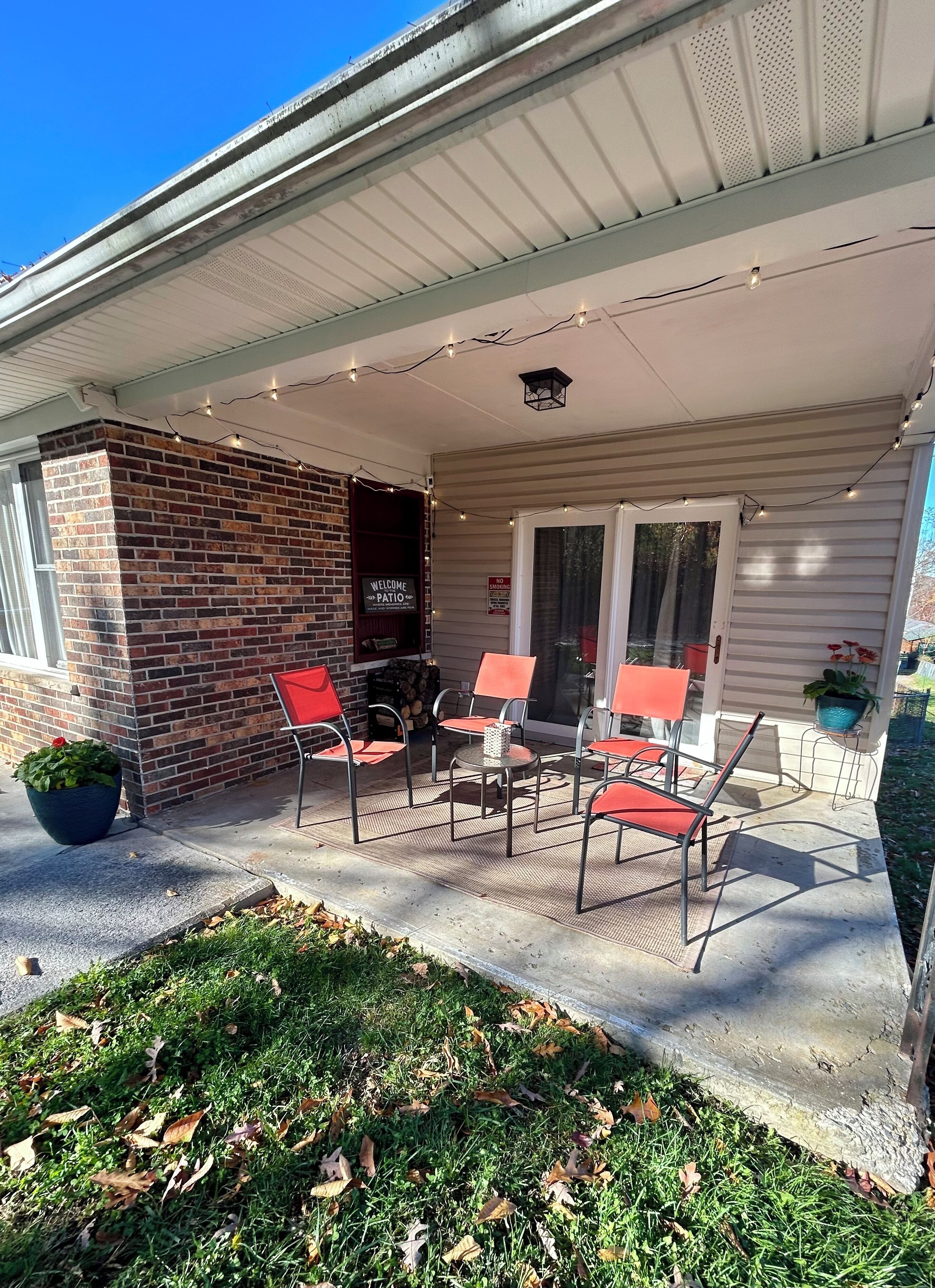 A covered patio with outdoor seating, a brick wall, and a welcome sign.