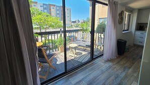 Un balcón con vistas a la ciudad, suelo de madera y una pequeña zona de estar.