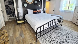 Un dormitorio con cama, mesitas de noche, un espejo y una ventana.