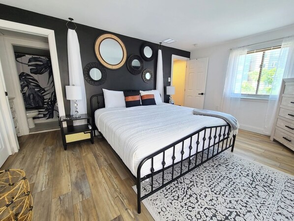Un dormitorio con cama, mesitas de noche, un espejo y una ventana.