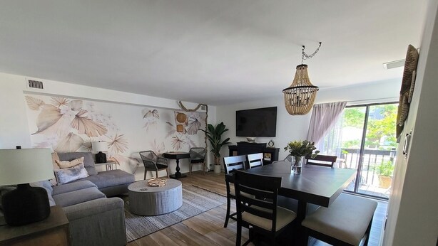 Una sala moderna con un sofá, sillones, una mesa de comedor y un televisor.