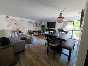 Una sala moderna con un sofá, sillones, una mesa de comedor y un televisor.