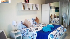 A bedroom with a bed, bedside tables, a nightstand, a mirror, and a wardrobe.