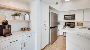 Una cocina moderna con armarios blancos, electrodomésticos de acero inoxidable y suelo de madera.