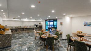 Un restaurant modern amb sòcols de marbre, cadires tapissades de verd i una barra amb una màquina de cafè.