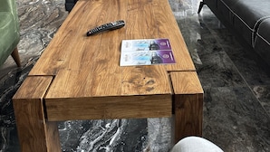 Rebedor modern amb taulell de recepció, zona de seients i taula de cafè de fusta amb comandament a distància i fulletons.