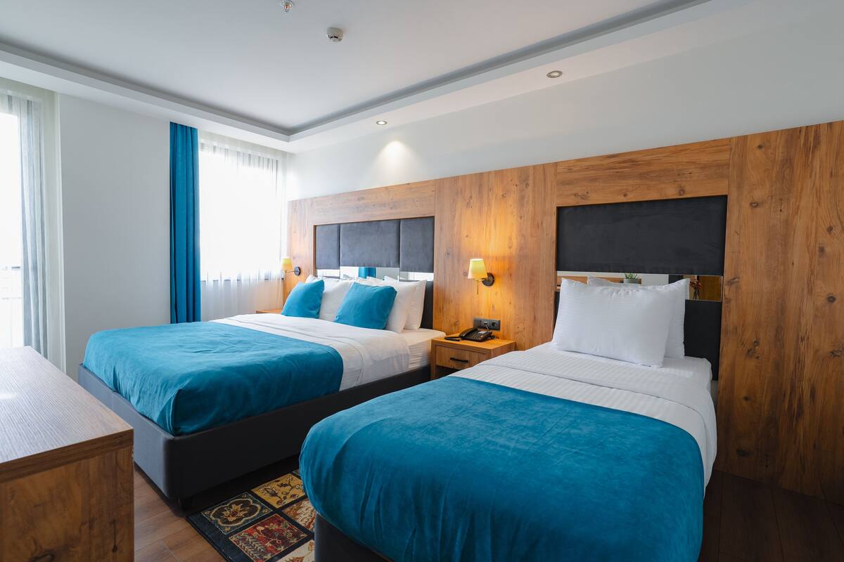 Ein Hotelzimmer mit zwei Betten, Holz-Kopfteilen und einem Nachttisch mit Lampe.
