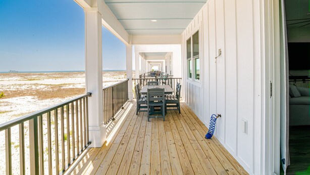 Un espace extérieur abrité doté d’une terrasse en bois, d’une table avec des chaises et d’une vue sur la plage.