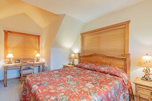 A bedroom with a large bed, two bedside tables with lamps, a wooden desk, and a window with blinds. - L004, 4Br, 4Ba Refreshing Roark Creek Cabin (Branson West)