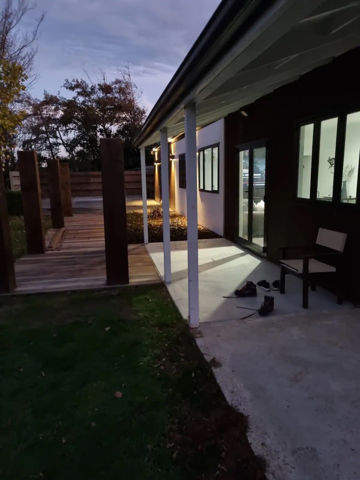 A modern building with a covered patio area, a wooden deck, and a bench.