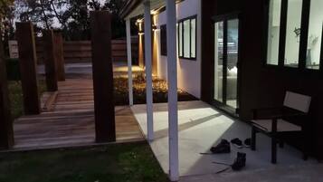 A modern building with a covered patio area, a wooden deck, and a bench.