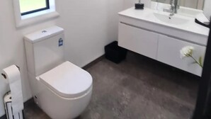 Un baño moderno con inodoro, lavamanos y espejo.