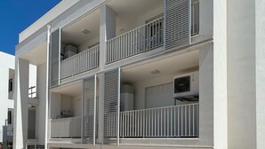 A multi-story building with balconies, air conditioning units, and a clear blue sky. - WePuglia – Appartamento GiuGio (Polignano a Mare)