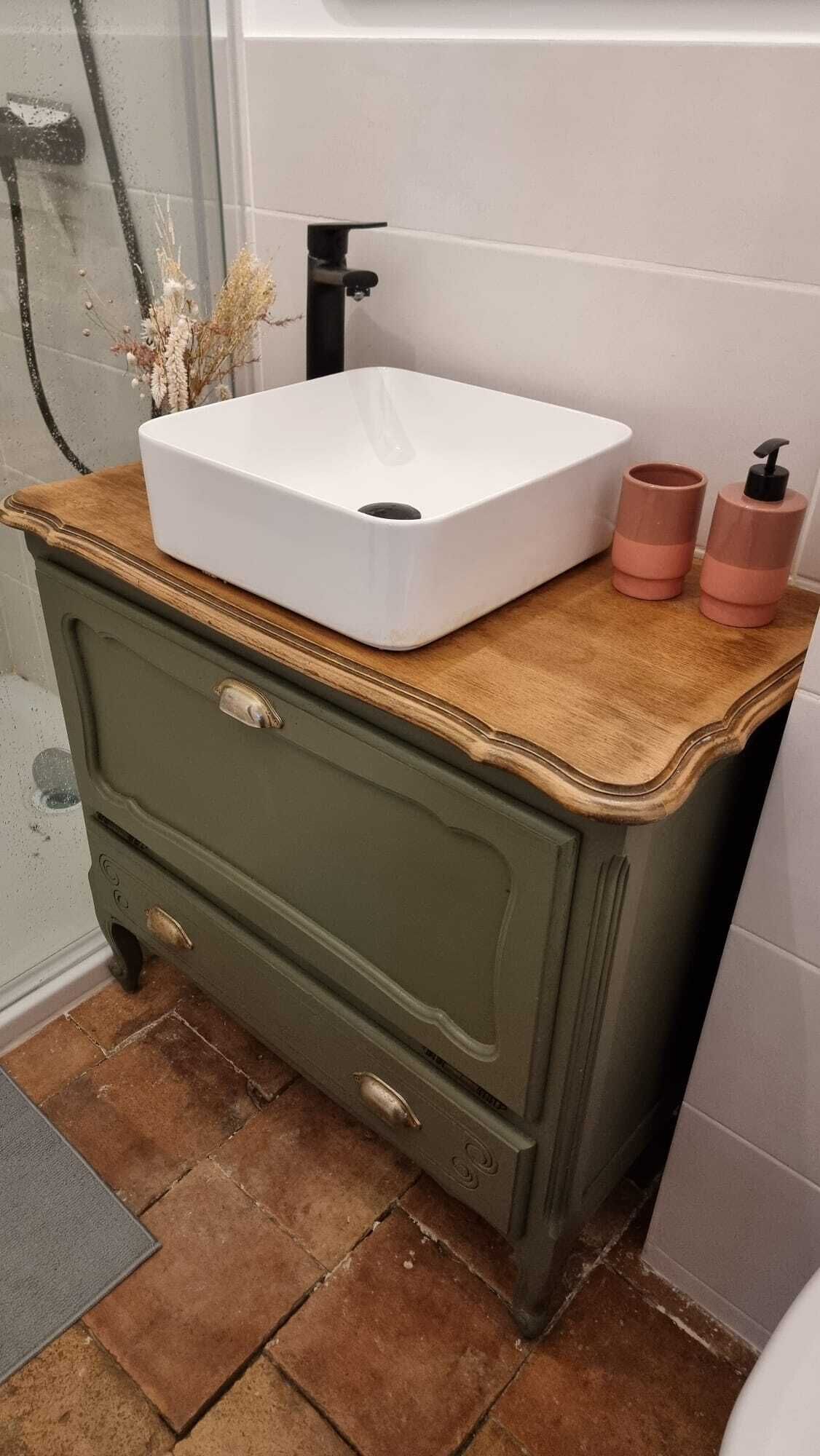 A bathroom with a white sink, two pink soap dispensers, and a green dresser.
