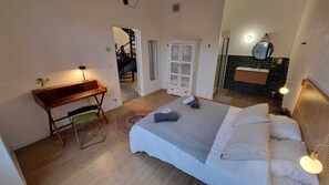 A bedroom with a bed, bedside table, lamp, and a view of a hallway.