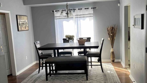 A dining area with a dark wood table, four chairs, and a bench. There is a chandelier above the table. - Location!! Minutes from L’Auberge/LSU/DOWNTOWN (Baton Rouge)