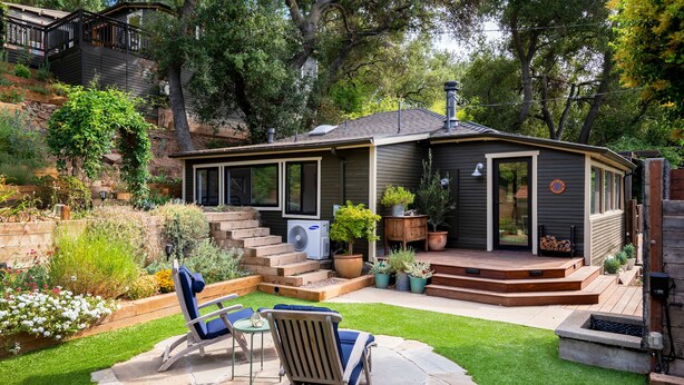 A covered patio with a stone floor, two lounge chairs, and a small table.