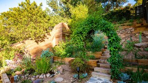 A garden with a wooden staircase, stone steps, and various plants.