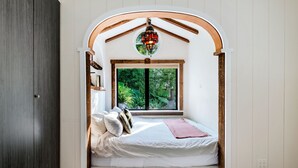 A cozy bedroom with a built-in window, a wooden ceiling, and a decorative lantern.