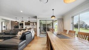 A modern living room with a black leather sofa, wooden dining table, and pendant lights. - Modern Farm Stay - South Coast (Yatte Yattah)
