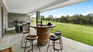 An outdoor patio with a round wooden bar, bar stools, and a grill. - Modern Farm Stay - South Coast (Yatte Yattah)