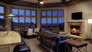 A spacious living area with a fireplace, large windows, and a television. - Spring Ski Week in the Canyons- Ski In/Ski Out (Park City)