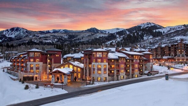 A multi-story lodge with a stone facade, multiple balconies, and a snow-covered landscape. - Spring Ski Week in the Canyons- Ski In/Ski Out (Park City)