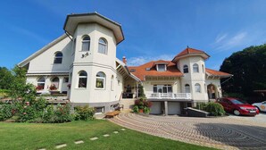 A large, two-story house with a prominent tower and a balcony. - Ferienwohnung mit Pool und Tischtennisplatte (Siófok)