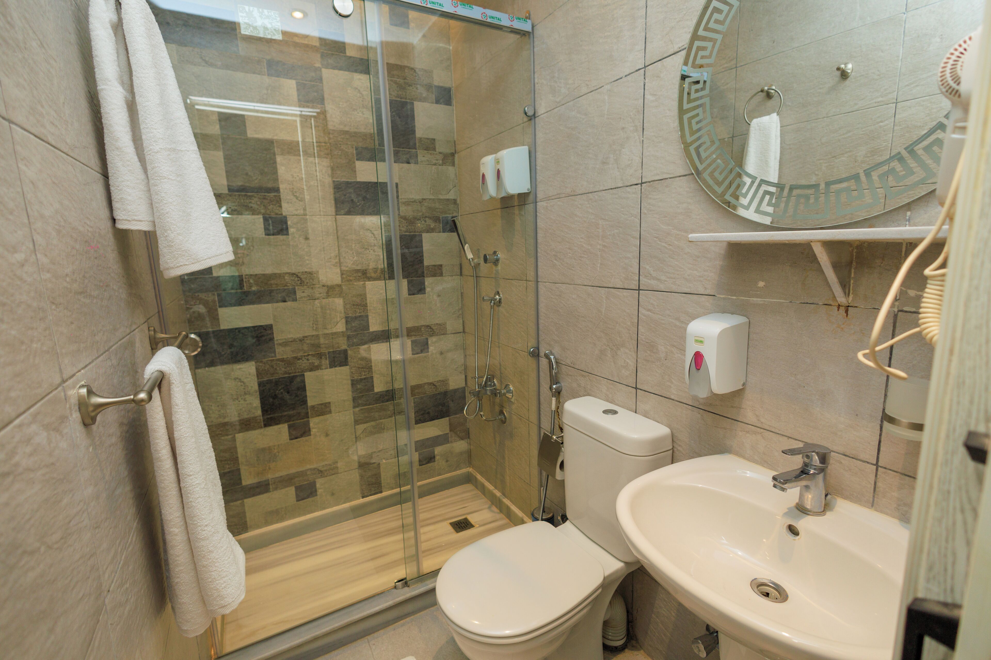 Un baño con ducha de vidrio, inodoro y lavamanos.