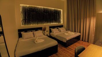 Habitación de hotel con dos camas, una obra de arte grande en la pared, piso de madera y vistas al exterior.