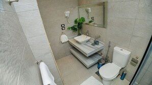 A modern bathroom with a white sink, a toilet, and a shower area.
