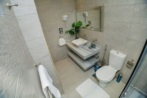 A modern bathroom with a white sink, a toilet, and a shower area.