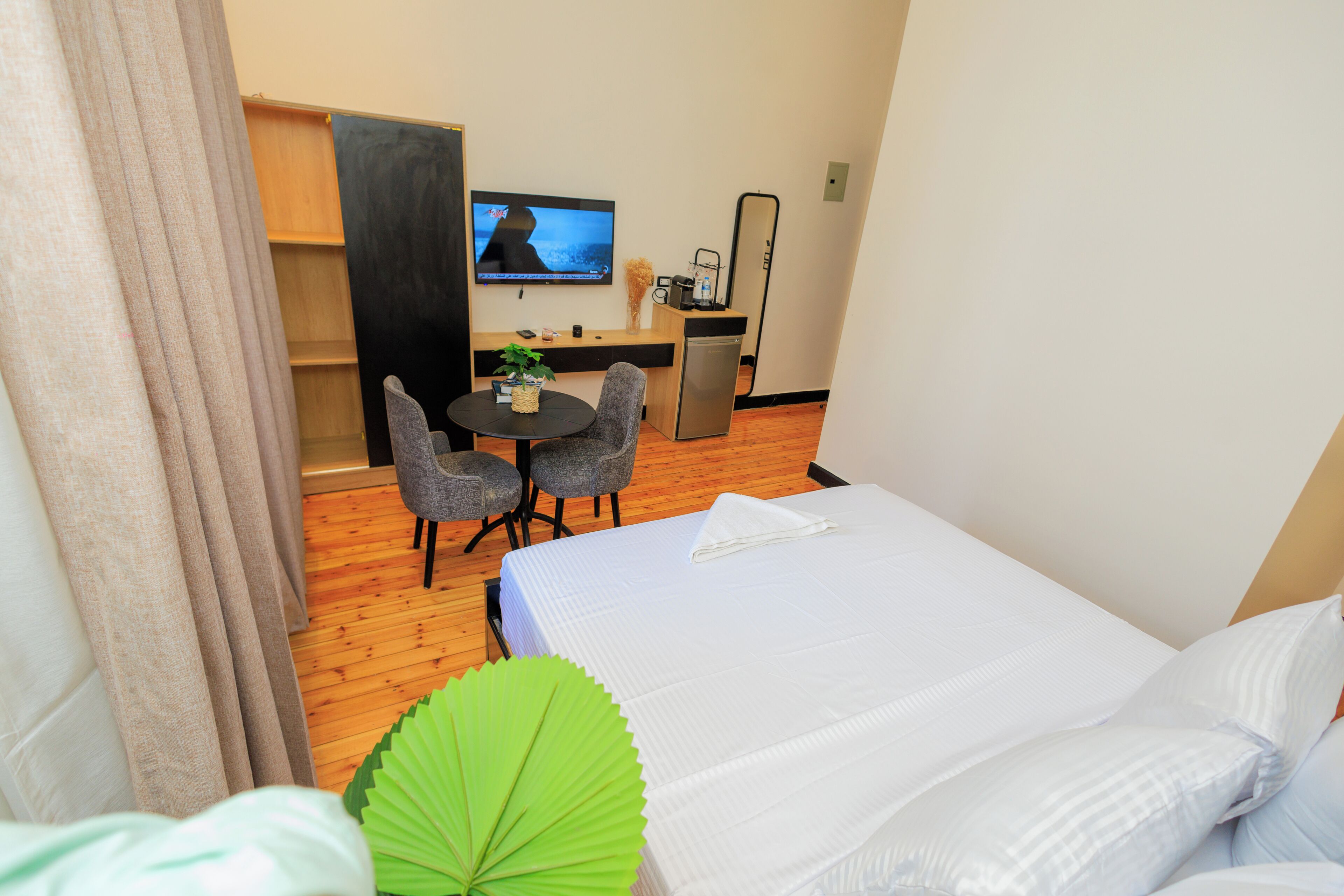 A hotel room with a bed, a desk with a chair, a television, and a small kitchenette.