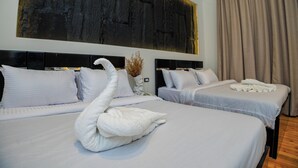 A hotel room with two beds, white linens, a large abstract painting on the wall, and a swan-shaped towel on the bed.