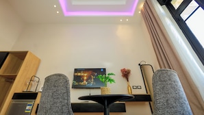 Ein modernes Hotelzimmer mit Flachbildfernseher, einem kleinen Tisch mit Pflanze und einem einzigartigen Deckengestaltung.