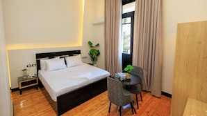 Ein Hotelzimmer mit Bett, Nachttisch, Sessel und einem kleinen Tisch mit Pflanze.