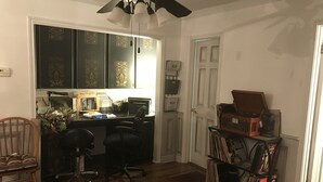 Un bureau à domicile équipé d’un bureau, de chaises, d’une bibliothèque et d’un ventilateur de plafond.